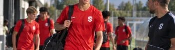 Young Siello Academy player arriving for training with a sports bag alongside program staff.